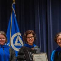 Provost Mili takes picture with 2 faculty women on stage